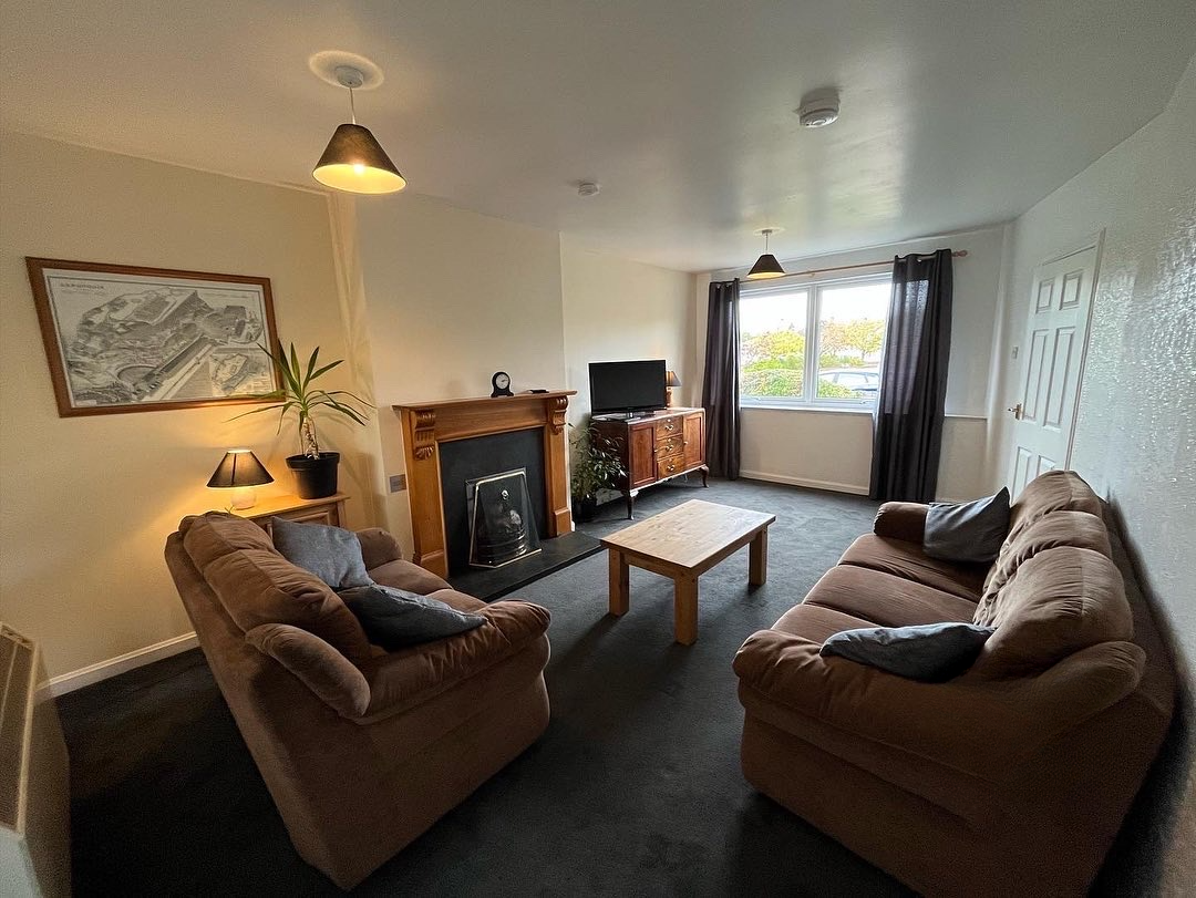 Bright living room in Inverness self-catering holiday let — two sofas, large window, garden view