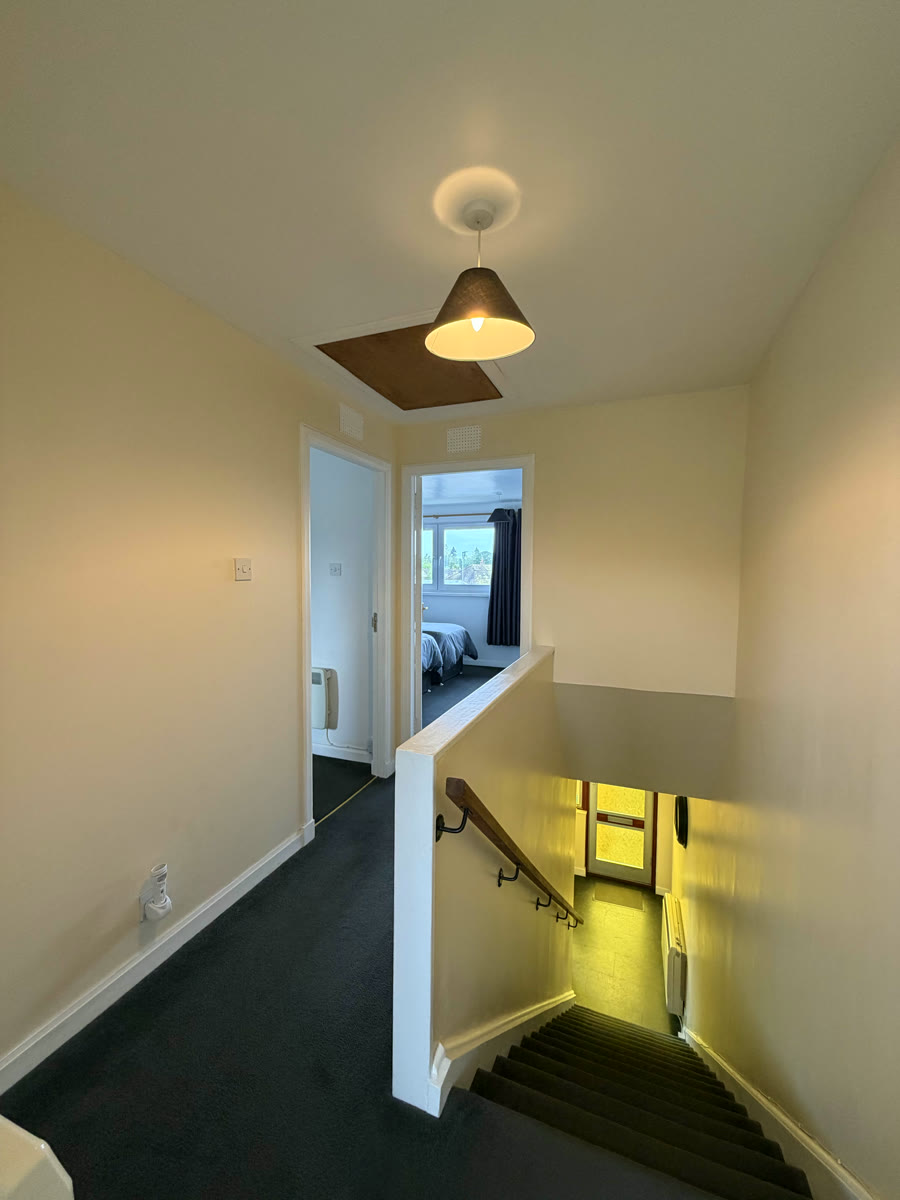 Upstairs landing in Inverness holiday home — carpeted stairs, pendant light